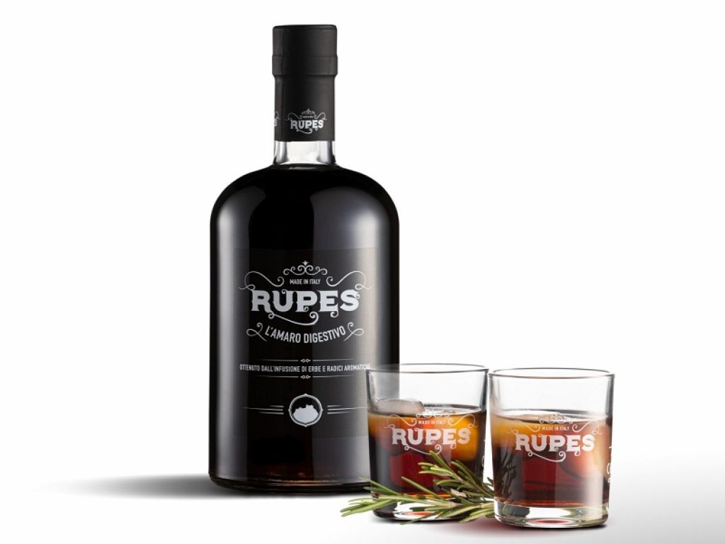 Una bottiglia di Amaro Rupes della Calabria con due bicchieri e una foglia di rosmarino