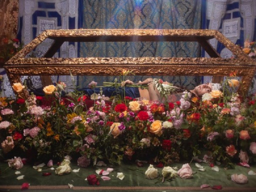 Achille Lauro steso in una bara di vetro circondata da rose