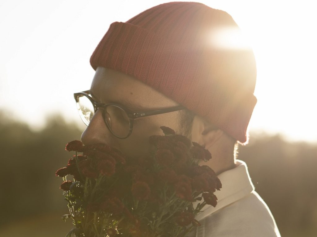 Il cantante Adult Matters con un mazzo di fiori in mano e cappello rosso in testa al tramonto