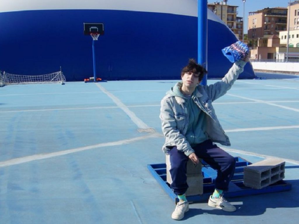 Il cantante Paul Giorgi seduto sotto al canestro di un playground