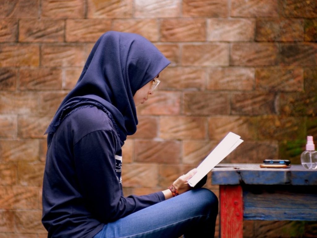 Una giovane studentessa con il velo in Afghanistan legge un libro