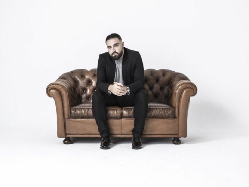 Il cantante Toni Veltri seduto su un divano in pelle marrone