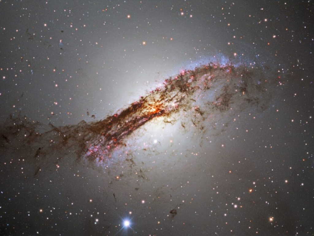 La banda di polveri, prova indiscutibile della fusione che ha originato la galassia Centaurus A come la osserviamo oggi, ospita la formazione di nuove stelle